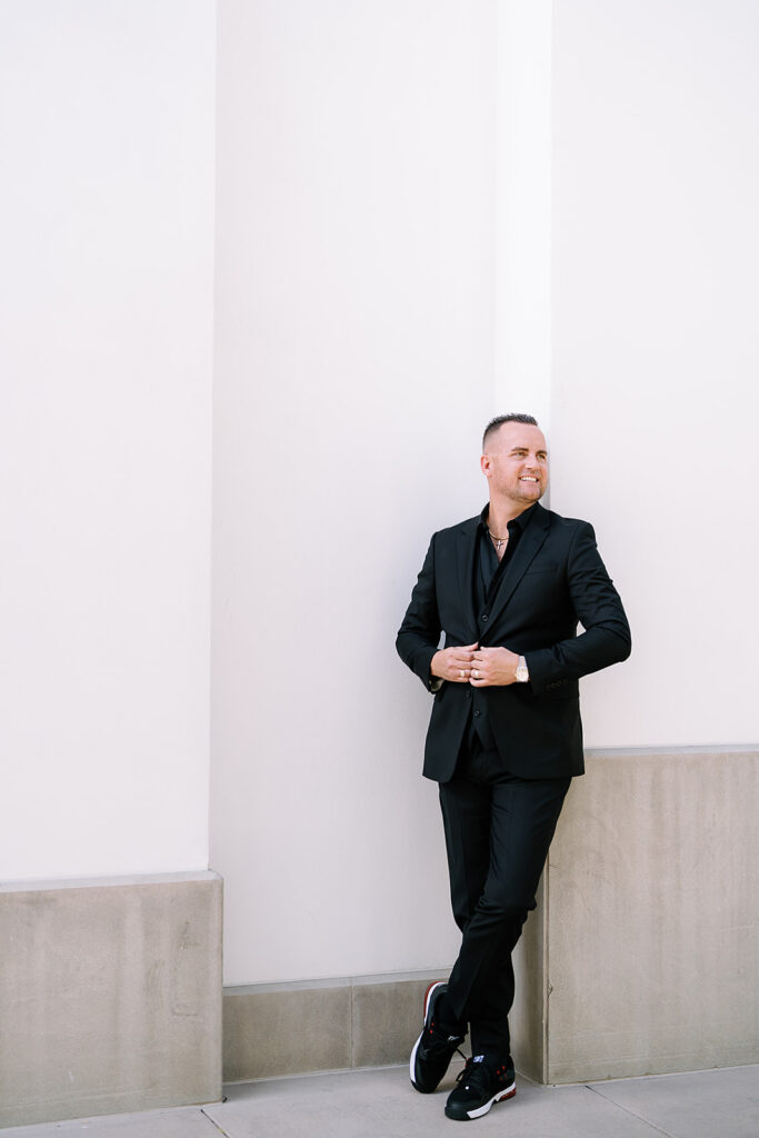 Steve Ord standing against a wall in an elegant suit